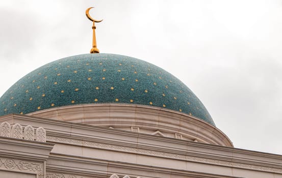 Close-up of the blue dome of the mosque with stars and golden crescent, white stone walls.