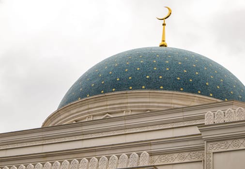 Close-up of the blue dome of the mosque with stars and golden crescent, white stone walls.