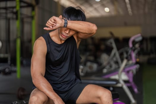 A young man taking a break after a kettlebell workout, reflecting on his fitness journey and commitment to health.
