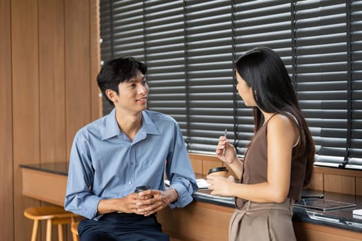 Two colleagues enjoy coffee while discussing work-related topics, highlighting casual business interactions and teamwork.