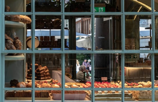 London, UK - May 13, 2025 - Exterior view of clear glass window display with Assortment homemade baked pastries, cake, bread in bakery shop. use it as your Wallpaper, Poster and Space for text, Selective focus.