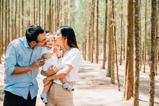 A man and woman holding a baby in a forest