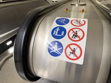 Close up of escalator safety instruction sign with multiple pictograms showing prohibited actions. Public transport safety concept with clear visual guidance for passengers
