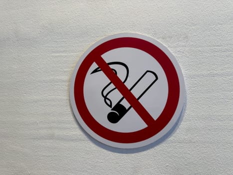 No smoking sign on light textured wall. Classic red prohibition circle with cigarette icon promotes health awareness, indoor safety, and smoke free environment compliance