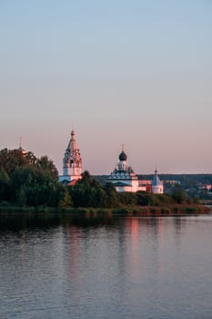 Vorsma, Nizhny Novgorod Region, Russia - 06.08.23. The historic Holy Trinity Ostrovoezersky Monastery is reflected in the waters of Lake Tuskanka at sunset.