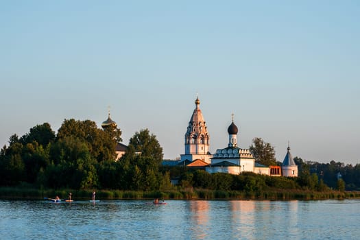 Vorsma, Nizhny Novgorod Region, Russia - 06.08.23. View of the Holy Trinity Ostrovoezersky Monastery with people on boats and SUPs.