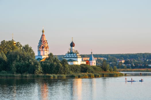 Vorsma, Nizhny Novgorod Region, Russia - 06.08.23. View of the Holy Trinity Ostrovoezersky Monastery with people on boats and SUPs.