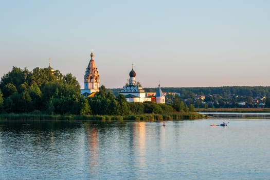 Vorsma, Nizhny Novgorod Region, Russia - 06.08.23. View of the Holy Trinity Ostrovoezersky Monastery with people on boats and SUPs.
