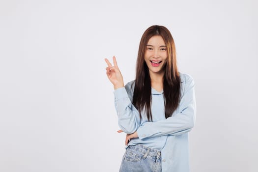 Victory sign and positive energy shine through as an Asian woman shows a gesture of victory with two fingers. Her optimistic smile brings out excitement and happiness.