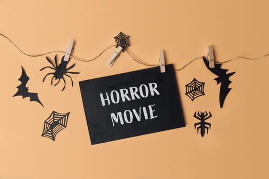 Blackboard with the words horror movie written on it. There are several spider and bat cutouts around the board