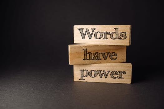 Three wooden blocks with the words words have power written on them. The blocks are stacked on top of each other
