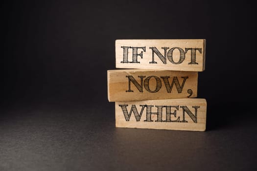 Three wooden blocks with the words if not now when written on them. The blocks are stacked on top of each other