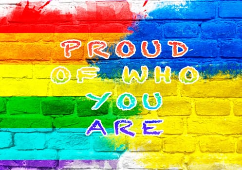 Colorful sign that says Proud of who you are. The sign is on a brick wall