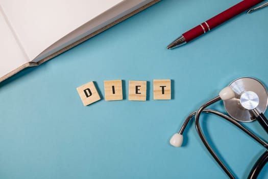 Blue background with a pen and a stethoscope. The word diet is written in wooden blocks on the table