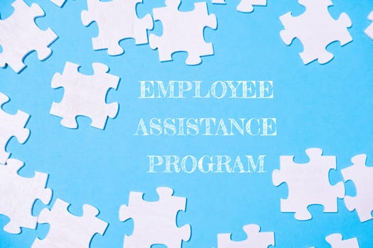 Jigsaw puzzle with the words employee assistance program written on it. The puzzle pieces are scattered across the image