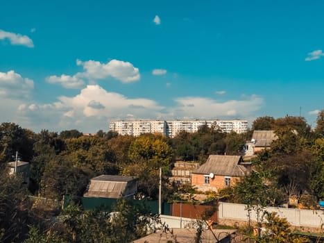 Small town with a few houses and a large building. The sky is blue and there are some clouds