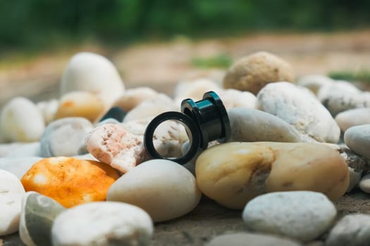 Two black ear plugs are on top of a pile of rocks. The rocks are white and grey