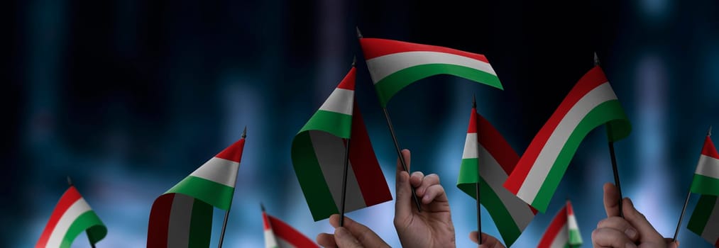Hungary flags in their hands on a blurred urban background. The photo illustration was created without the use of artificial intelligence, only using Photoshop.