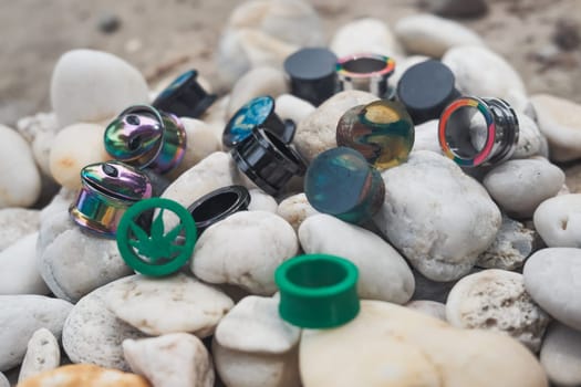 Pile of earrings with one that says "weed" on it. There are many different colors and designs