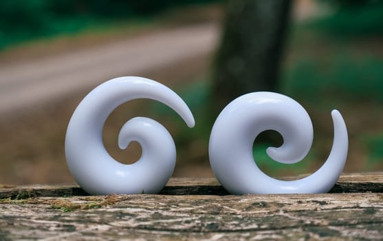 Two white earrings with a curved design. One is on the left and the other is on the right