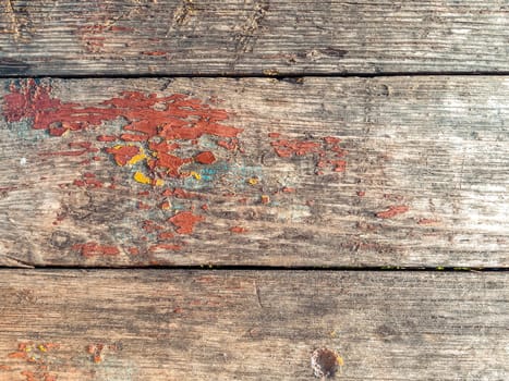 Wooden surface with a red and blue paint splatter. The paint is on the wood and has a greenish tint
