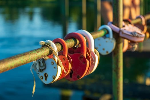 Heart-shaped love padlocks secured on a bridge railing symbolize everlasting commitment and romance. Selective focus.