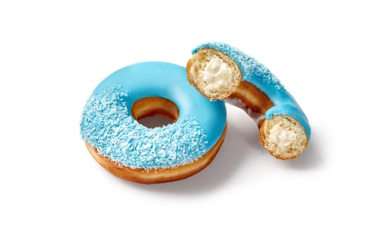 Delicious donuts with blue icing and coconut flakes, one with a bite taken out, revealing a creamy filling, lie on a white backdrop