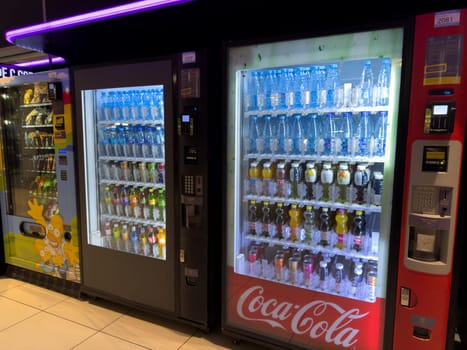 Moscow, Russia, April 25, 2025: Vending machines offering bottled water, soda, juice and snacks in brightly lit shopping mall, including Coca Cola branded dispenser and modern payment terminals
