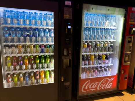 Moscow, Russia, April 25, 2025: Illuminated vending machines offering wide range of bottled drinks including water, juice, tea and soda, with Coca Cola branding in shopping mall setting