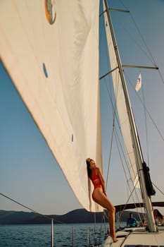 Turkey, Marmaris, 06 October 2020: A beautiful girl in a red swimsuit poses on the bow of a sailing boat, a sexy figure, mountains in the background on a sunny day. High quality photo