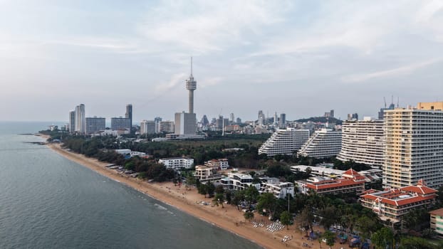 Tourists enjoying pattaya beach at dusk with the city skyline dominating the coastline, offering a stunning view of the vibrant cityscape meeting the tranquil sea