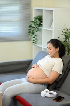 Pregnant woman gently cradling her belly, symbolizing bonding, and anticipation of motherhood.