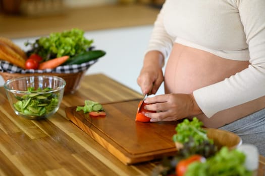 Pregnant woman preparing healthy meal in kitchen.