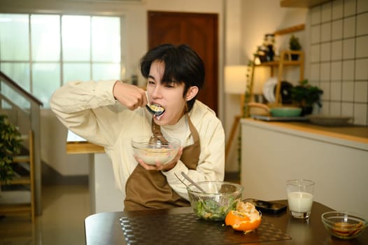 Young asian man enjoying healthy breakfast at home.