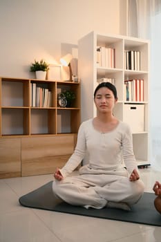 Teenage asian girl meditating in a calm and cozy home environment.