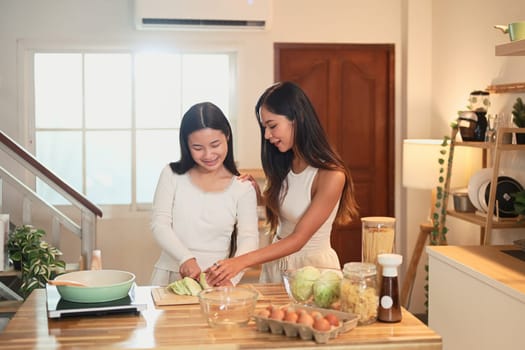 Mother and teenage daughter preparing a healthy meal together in a warm kitchen.