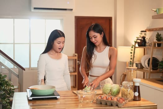 Mother and teenage daughter preparing a healthy meal together in a warm kitchen.