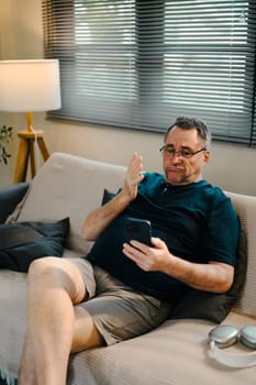 Elderly man having video call or checking messages on his smartphone.