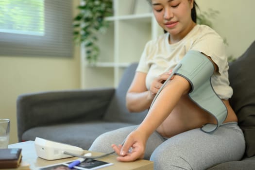 Pregnant woman checks her blood pressure at home. Maternal wellness and health care concept.