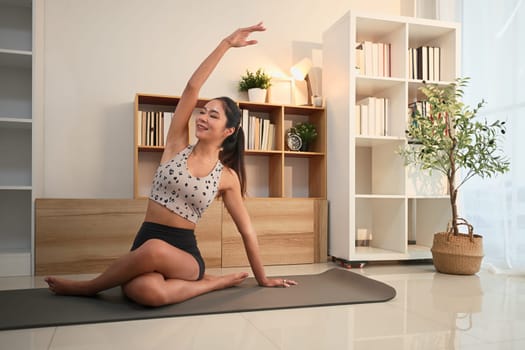 Beautiful asian woman practicing elegant yoga stretches in a peaceful living room.
