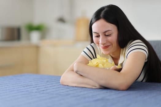 Gluttonous asian woman hugging potato chips in the kitchen at home
