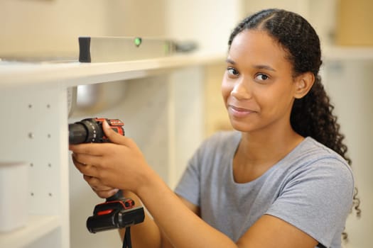 Portrait of a black woman reforming house looks at camera in the kitchen