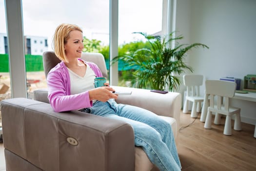 Woman enjoys quiet time with a cup in bright room.