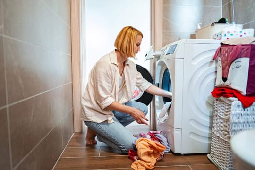 A woman is organizing clothes in a modern laundry space.