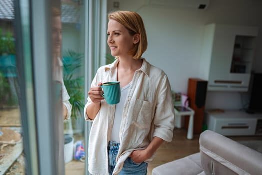 Relaxing by the window, savoring a warm cup of coffee.