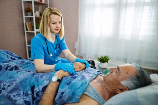 Gentle nurse comforts senior man in a cozy healthcare setting.