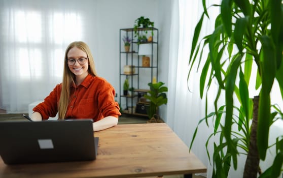 Woman smiles while typing in a warm and inviting home office space.