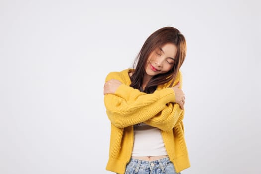 Hug yourself with ease, hug your heart with warmth. A confident Asian woman embraces herself, showing relaxation and gentle joy in a quiet, carefree moment. isolated white background