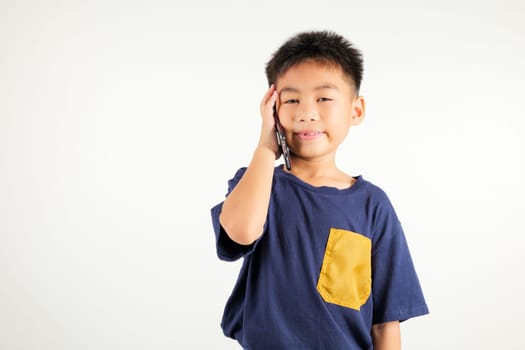 Happy Asian portrait cute young kid boy smiling excited talking smart mobile phone studio shot isolated on white background, Thai child calling gesture on smartphone