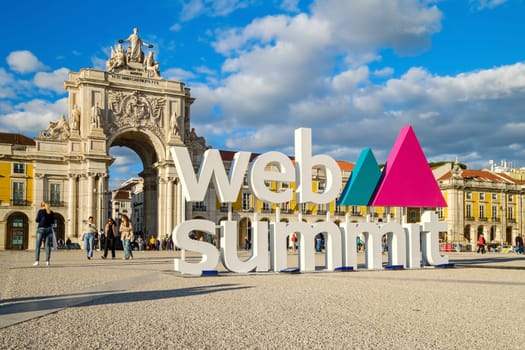Nov 13, 2024 - Lisbon, Portugal: Big sign Web Summit near iconic Arco da Rua Augusta, beautiful blue sky with some clouds. People walking and taking photos, event, technology, innovation, interaction, exploration, international conference, networking